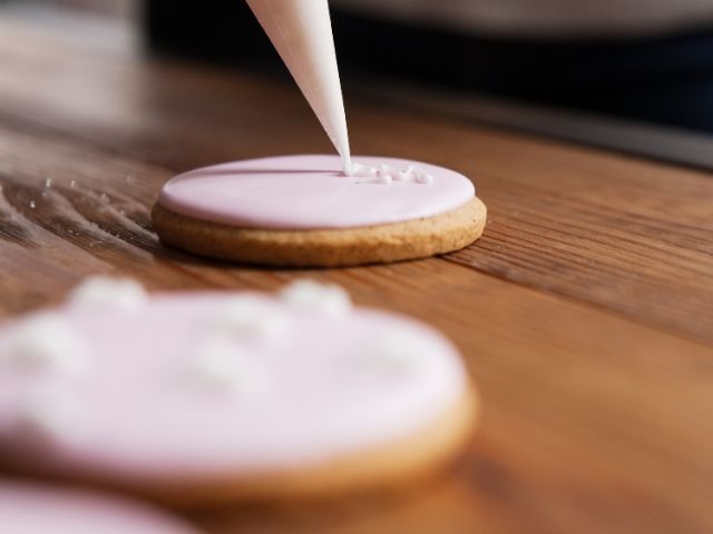 Placing icing on Gingerbread cookie. Keep reading to learn about the Disney World Gingerbread house display on Theme Park Hipster!