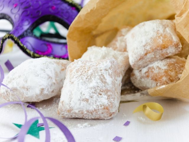 New Orleans Mardi Gras Origins with Beignets sitting next to mask.