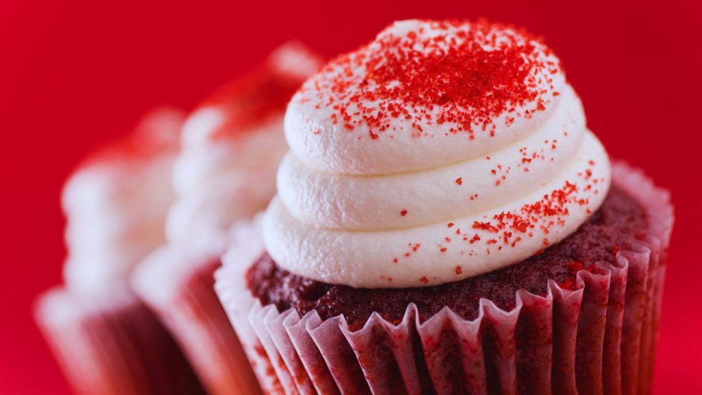 Red velvet cupcake with red sprinkle on red background at disney