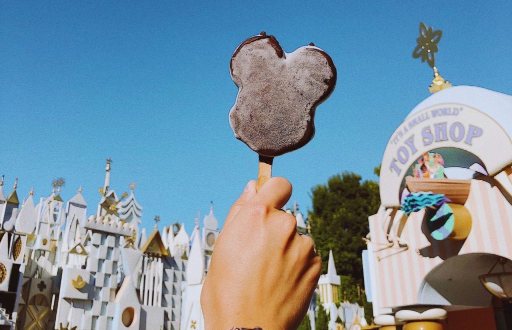 Mickey Mouse Ear Ice Cream Bar in Front of Small World Disneyland. Keep reading for the full guide to how to plan a California road trip.