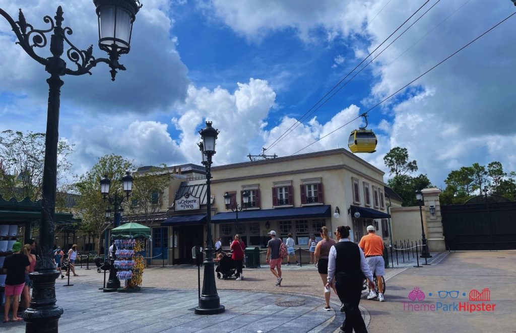 La Creperie de Paris with Disney Skyliner in the Background at Epcot. Keep reading to get the full Disney World Skyliner Guide with the Cost, Hours, Tips and more!