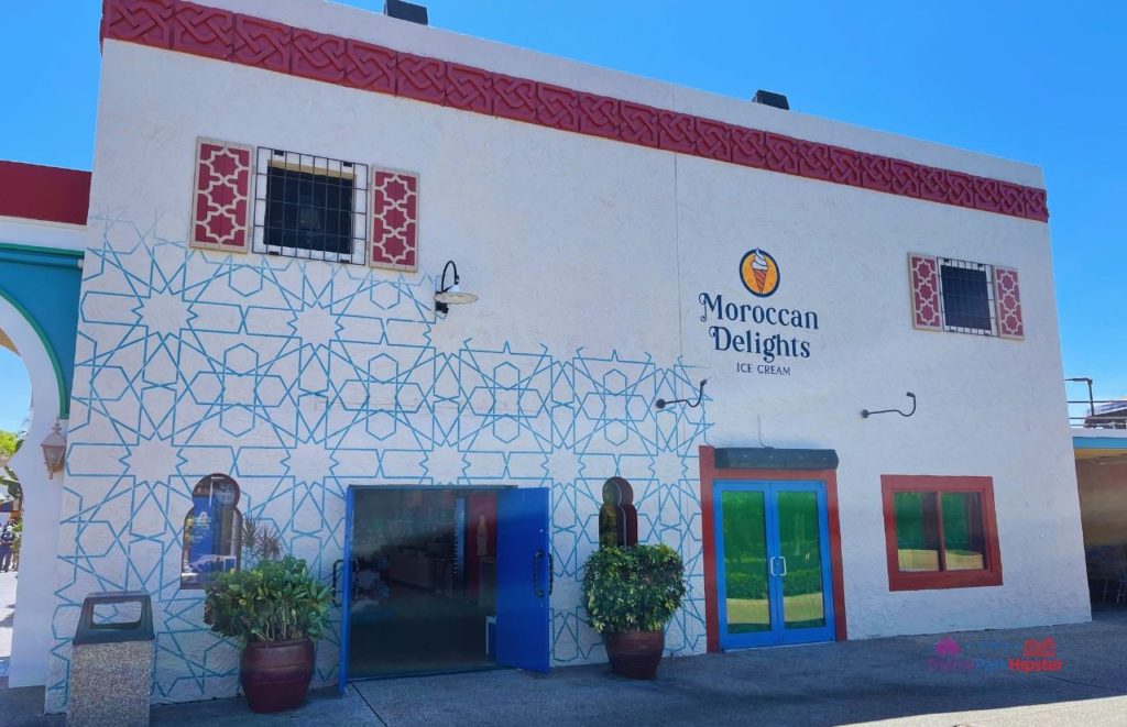 Moroccan Delights Ice Cream entrance with a white building and red and blue design and planters at  Busch Gardens Tampa Bay. Keep reading to discover more about restaurants at Busch Gardens Tampa.