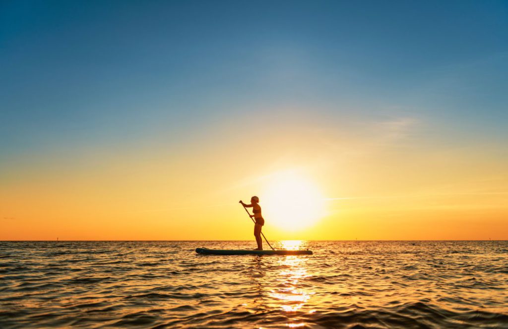 Honeymoon Island State Park, Florida with lady on paddleboat. Keep reading to find out the best places to go on a solo trip in Florida. 