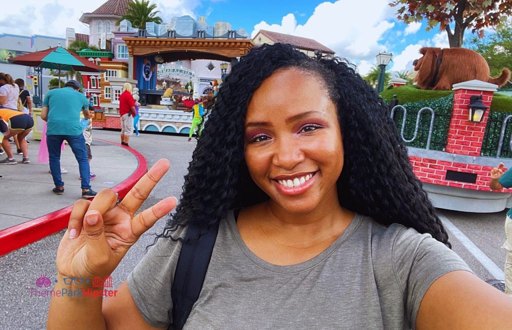 NikkyJ, author of Theme Park Hipster, smiling and giving the peace sign in front of the Secret Life of Pets float at  the Universal Superstar Parade. Keep reading to to find out more Mistakes to Avoid at Universal Orlando Resort!