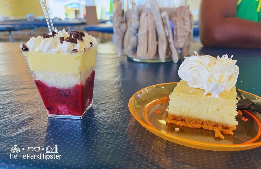 Cedar Point Nights Beach Party and Lake Erie Luau Berry Parfait topped with whipped cream and chocolate chips next to spongy yellow cake on orange plate