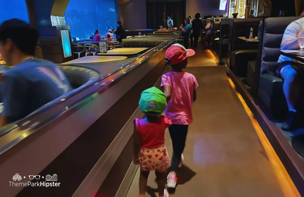 SeaWorld Orlando Resort Sharks Underwater Grill dining room with little girls walking. Keep reading to find out more about Sharks Underwater Grill at SeaWorld Orlando.